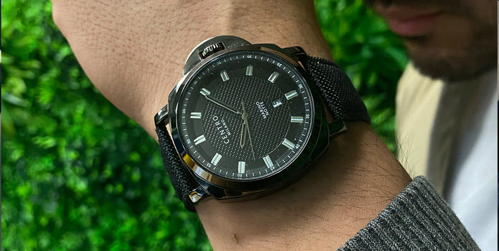 Person wearing a black wristwatch with a textured dial and bold hour markers.